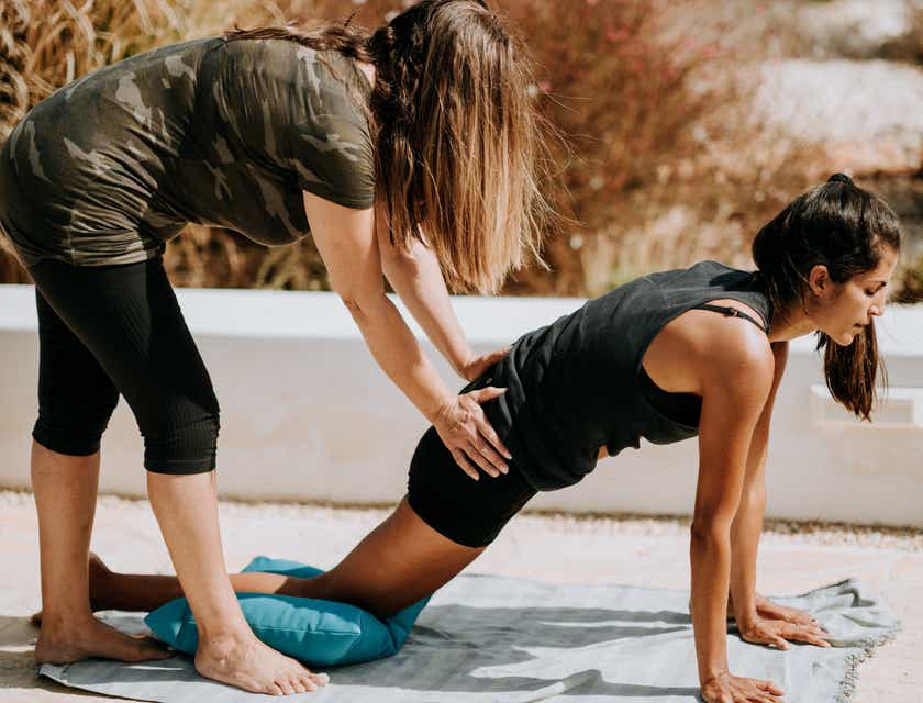 Trener pomagająca kobiecie wykonać pozycję jogi w ramach coachingu.