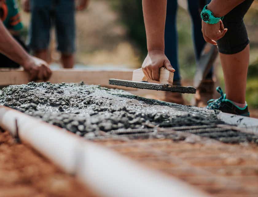 Un ouvrier du bâtiment lisse du béton humide avec un outil sur un chantier de construction.