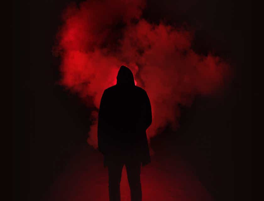 A figure backlit by cool red lighting and a smoke machine.