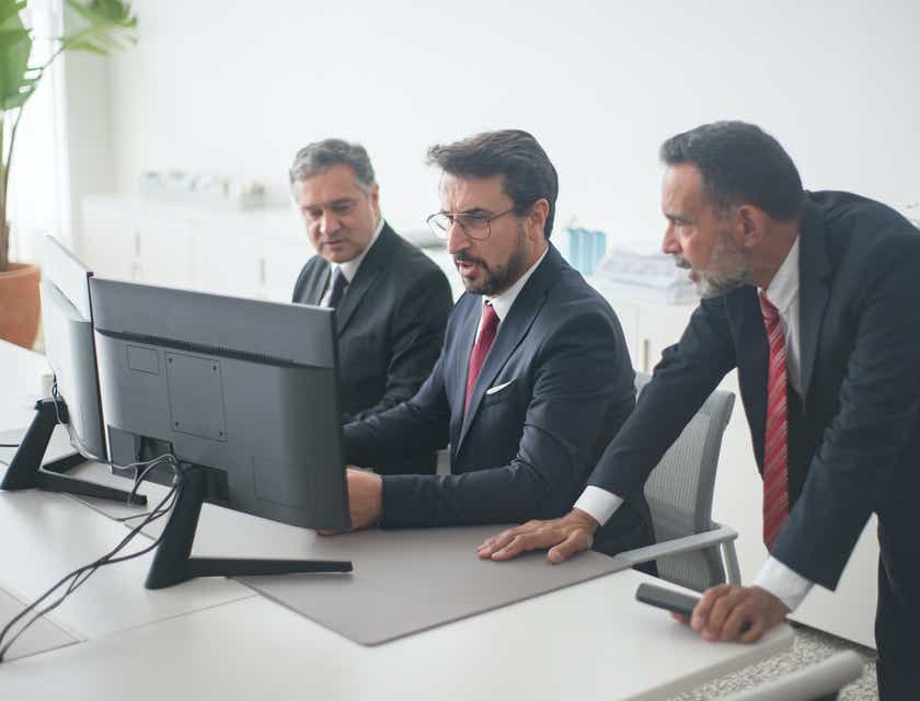 Drei Angestellte eines Unternehmens halten ein Meeting und schauen auf einen Computerbildschirm.