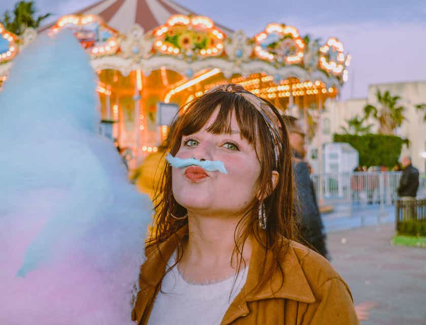 Una joven con una pieza de algodón de azúcar sobre sus labios de forma divertida.