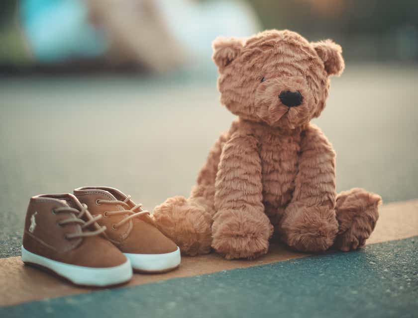 Un paio di scarpette da bambino accanto a un tenero orso di peluche.