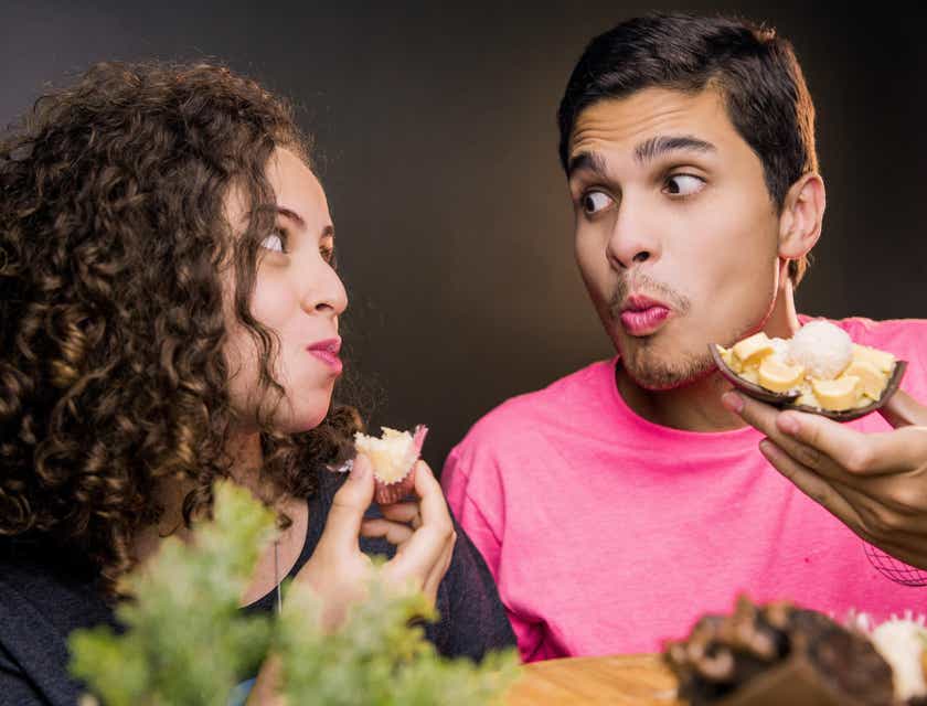 Ein Mann und eine Frau, die sich über eine Dating-App kennengelernt haben, essen Snacks und schauen sich dabei tief in die Augen.