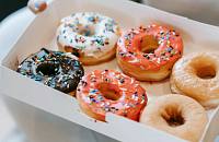 A person holding a box of donuts in their hands.