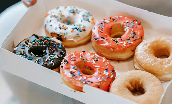 A person holding a box of donuts in their hands.