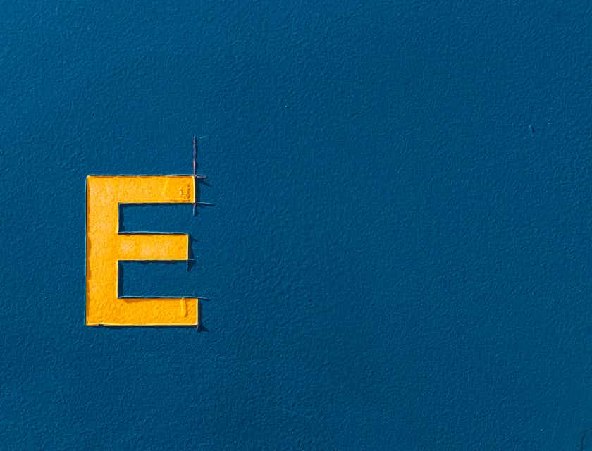 Żółta litera „E” namalowana od szablonu na ciemnoniebieskim tle.