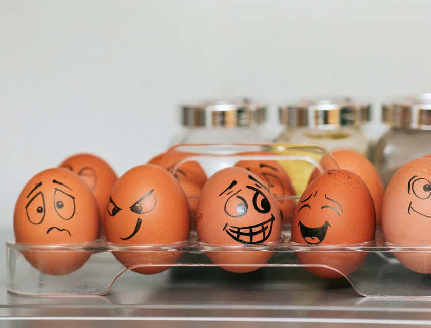 Des œufs dans un support avec des visages amusants dessinés dessus.