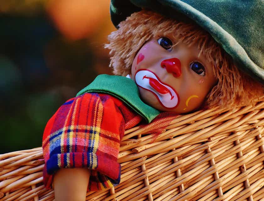 Una bambola con la faccia triste truccata da clown.