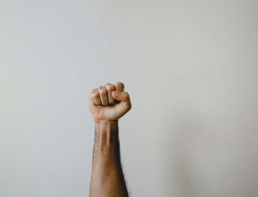 Un hombre mostrando su durabilidad al alzar su puño en señal de victoria.
