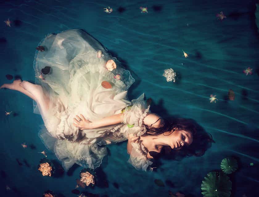 Eine Frau in einem traumhaften Kleid macht in einem flachen Becken ein Fotoshoot.