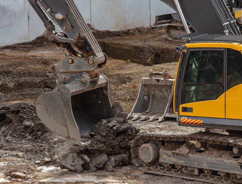 A black and yellow excavator moving soil.