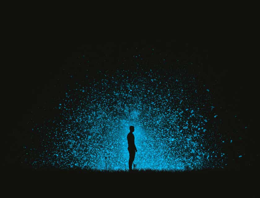 Eine Person steht im Dunklen vor einer eindrucksvollen, blauen Farbexplosion.