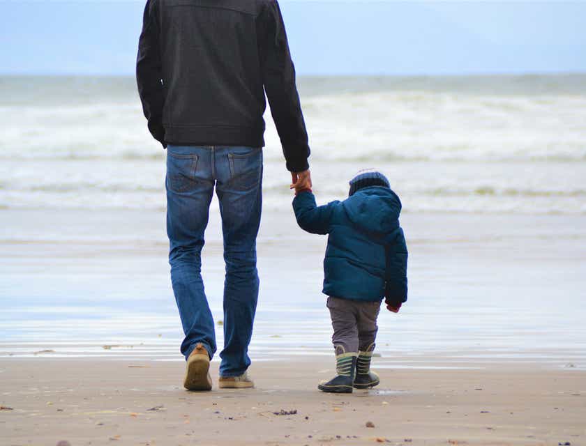 A father and son walking on a beach.