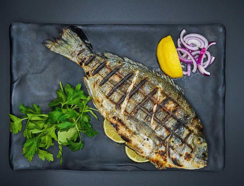 Peixe grelhado em um prato na mesa de um restaurante de peixe.