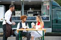 People sitting outside a food truck.