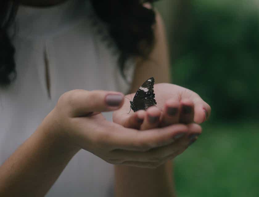Una donna che tiene con gentilezza in mano una farfalla.