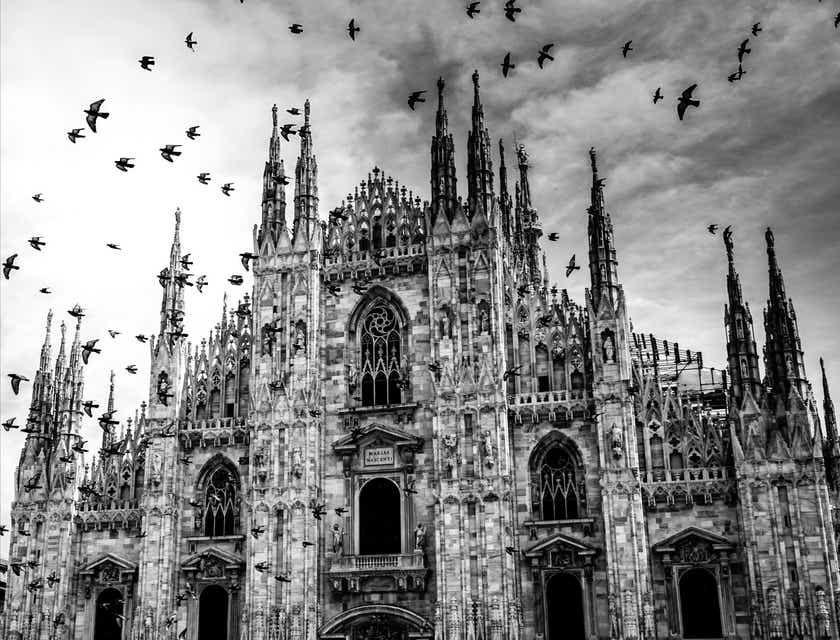 De gotische kathedraal van Milaan vanwaaraf een zwerm vogels opstijgt.