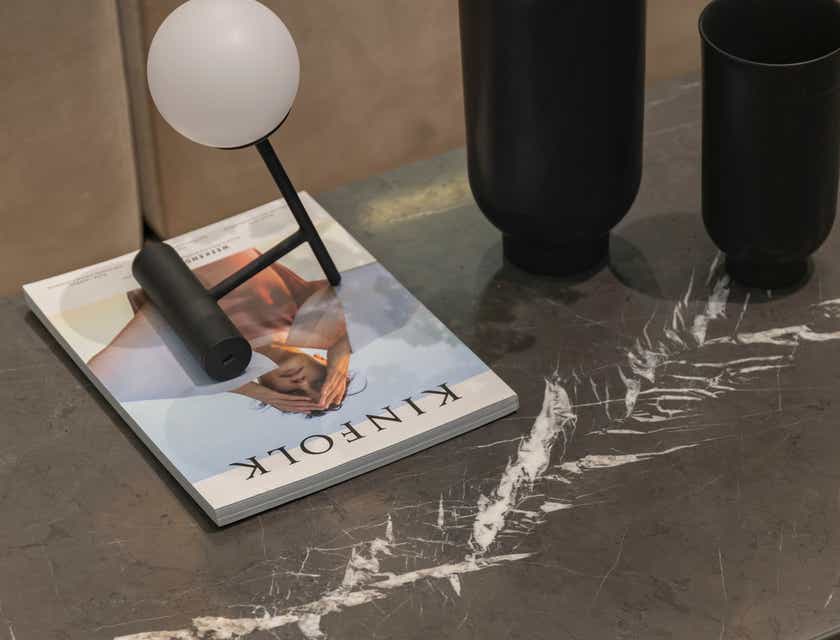 A magazine and light fixture displayed on a gray granite table.