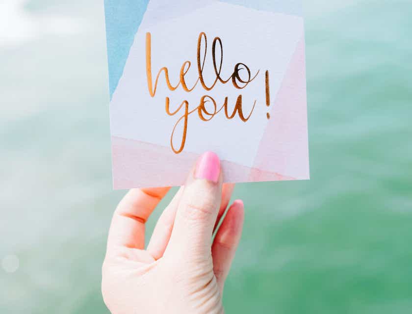 A person holding up a greeting card that says, "hello you!"