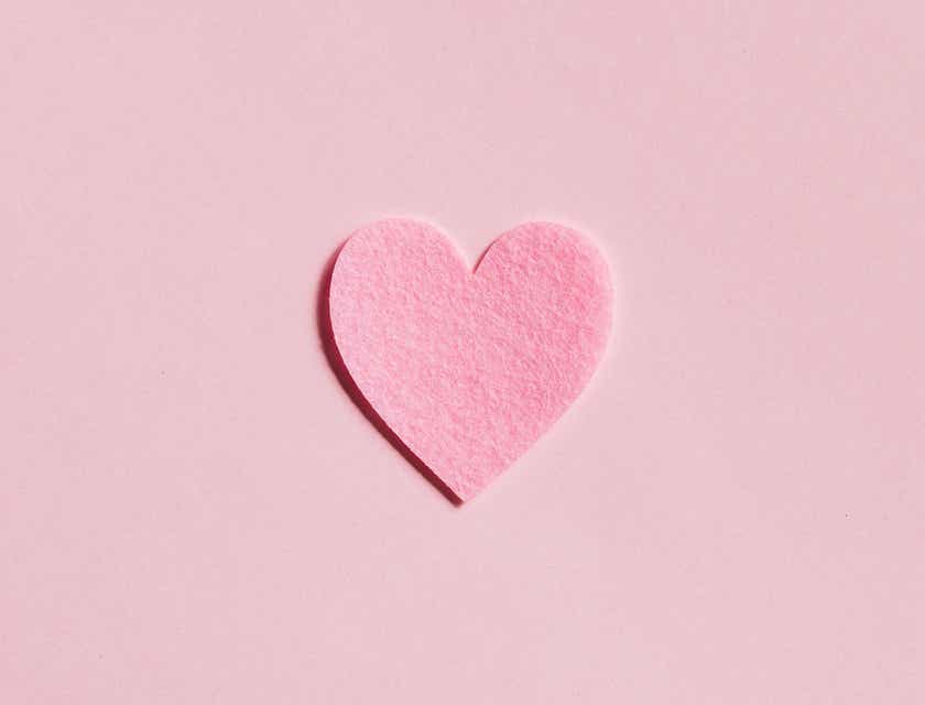 Wycięte papierowe serce na różowym tle.