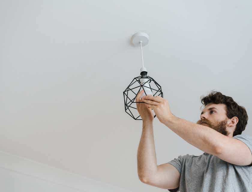A home services employee installing a ceiling light.