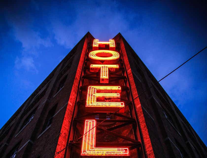 Eine vertikale Leuchtreklame auf einem hohen Gebäude mit dem Schriftzug „Hotel“ in Großbuchstaben.