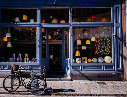 Storefront with lights in the window and a bicycle in the street.
