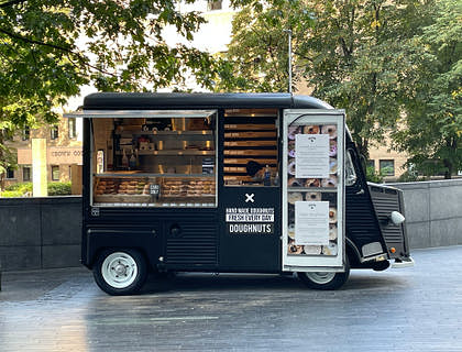 A new business startup selling donuts from a small black food truck.