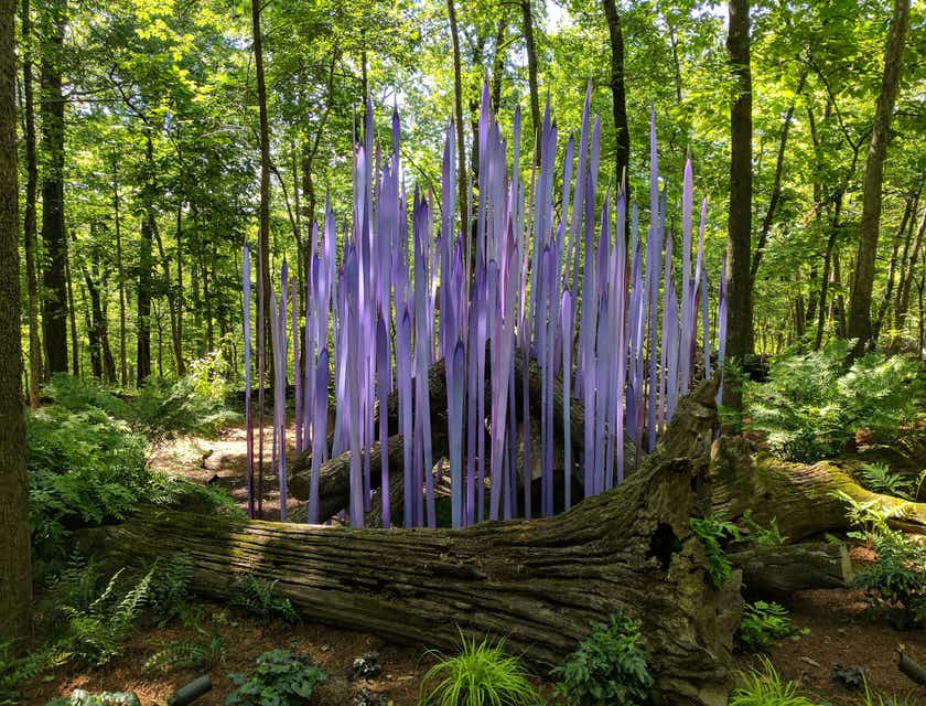 Unas formaciones verticales de color púrpura detrás de un árbol desarraigado en un bosque.