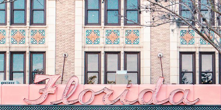 Person standing across the street from a building with a Florida sign.