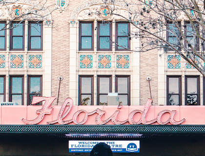 Person standing across the street from a building with a Florida sign.
