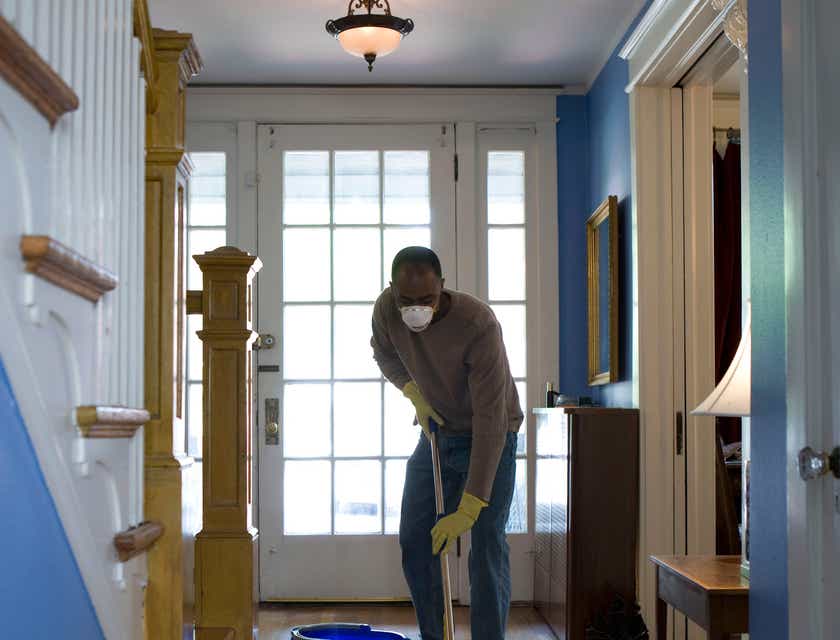 Ein Mitarbeiter einer Reinigungsfirma reinigt den Eingangsbereich eines Hauses.