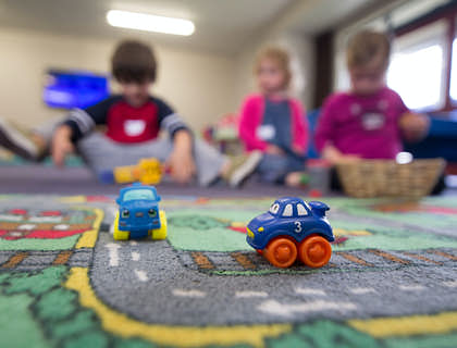 three young children sitting and playing games on a carpet
