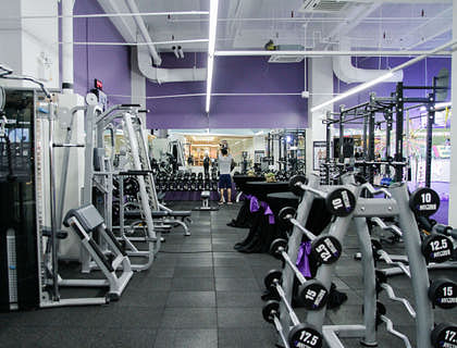 A guy lifting weights surrounded by fitness equipment inside a gym.