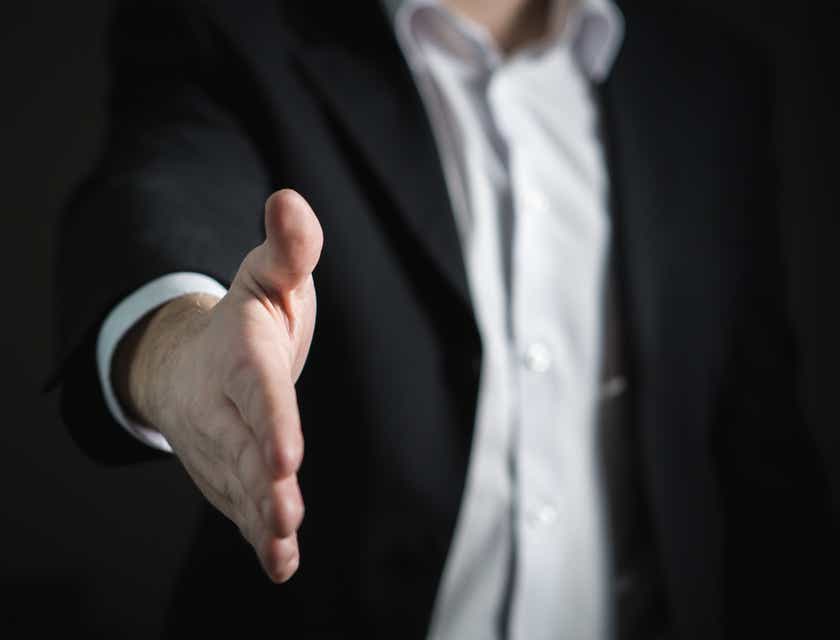 Un broker assicurativo che tende la mano in attesa di una stretta di mano.