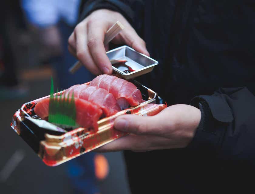 Eine Person hält ein Take-away von einem japanischen Restaurant in den Händen.