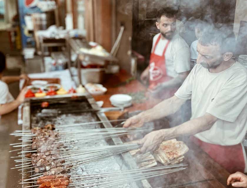 A group of men cooking kebabs at a restaurant.