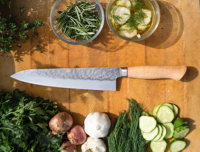 Un coltello da cucina contornato da spezie ed erbe.