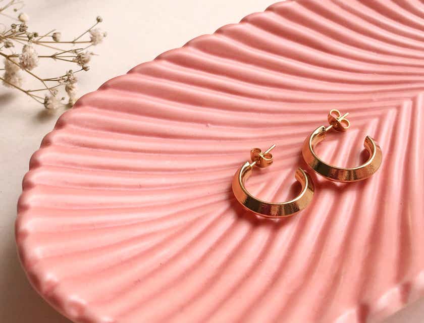 Gold hoop earrings in a pink bowl.