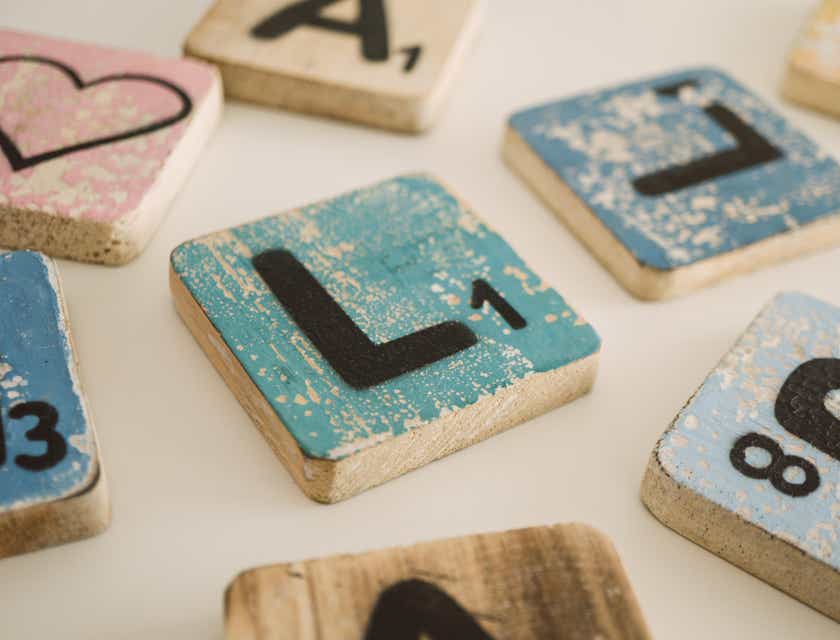 Ein farbiger Holzblock mit dem Buchstaben „L“ liegt neben ähnlichen Blöcken auf einem Tisch.
