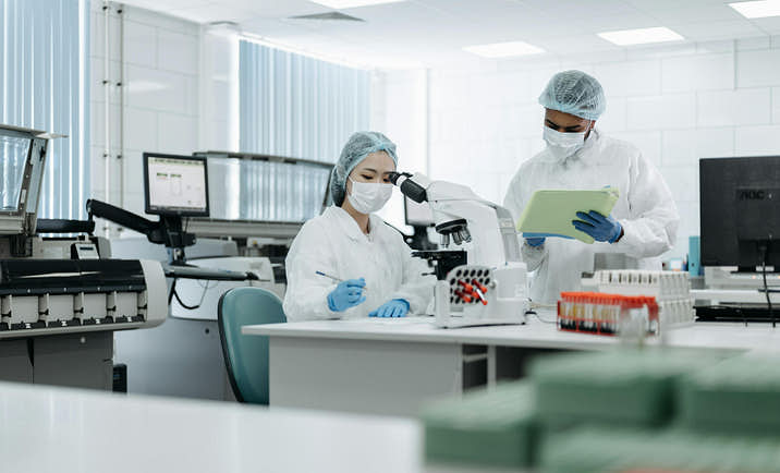 Two scientists working in a laboratory and taking notes on their project.