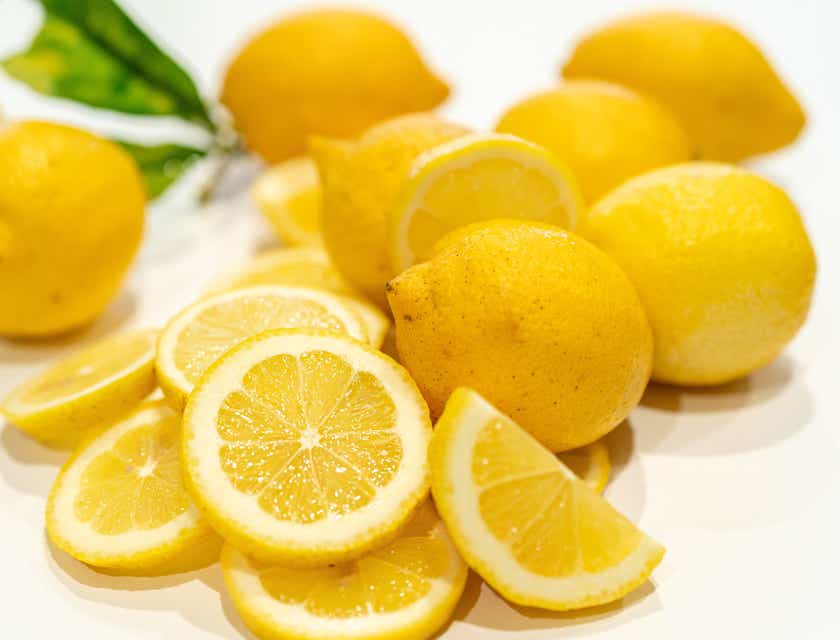 Whole and cut lemons against a white background.
