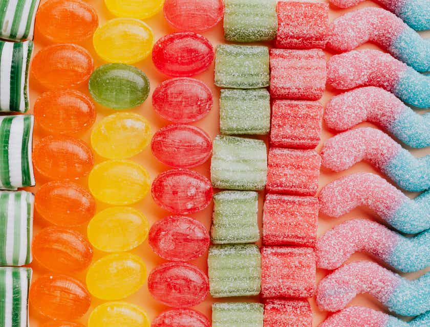 Tanti dolci e caramelle di colori diversi disposti in fila.