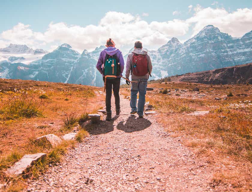 Due escursionisti che camminano su un sentiero verso una montagna innevata.