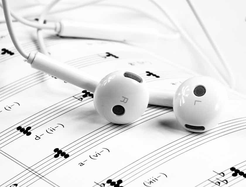 Sepasang earphone putih tergeletak di atas partitur musik.