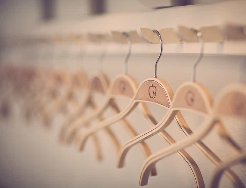 Sederet hanger baju berwarna cokelat di sebuah railing.