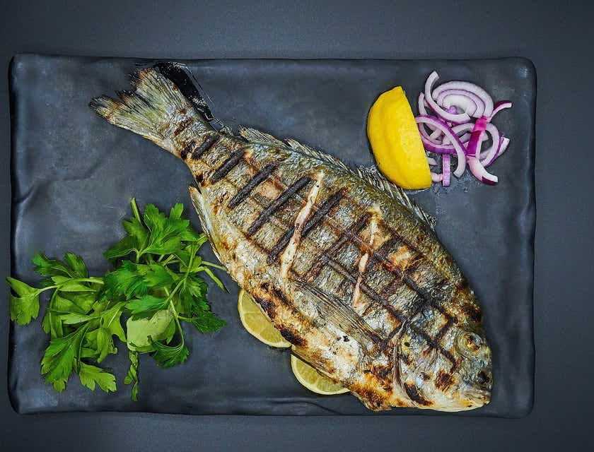 Ikan bakar disajikan di atas piring di sebuah restoran ikan.