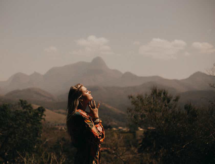 Una mujer orando con mucha fe en un valle.