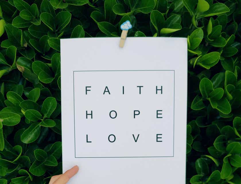 Hand holding a sign that reads "Faith Hope Love" in a business based on religion.