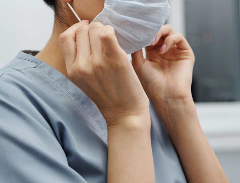 Enfermera colocándose un cubrebocas en la boca.